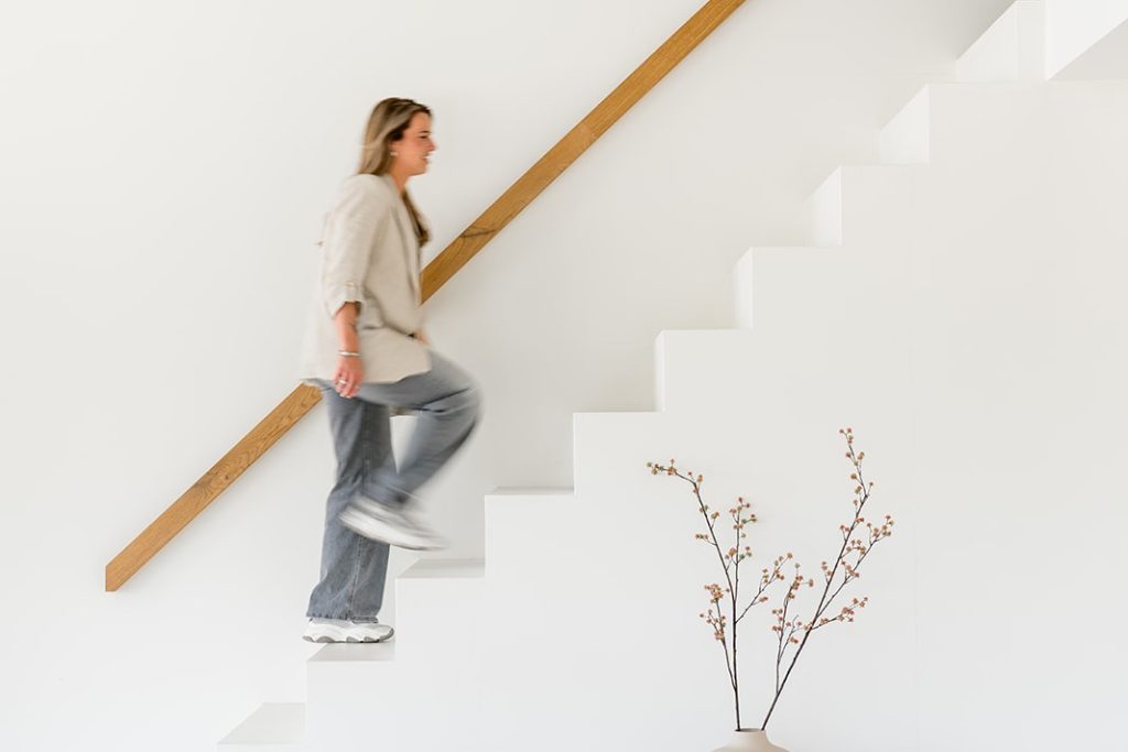 Vrouw loopt trap op in minimalistisch interieur