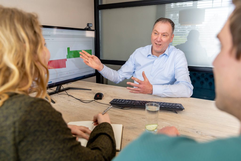 Man bespreekt grafiek met collega's aan tafel.