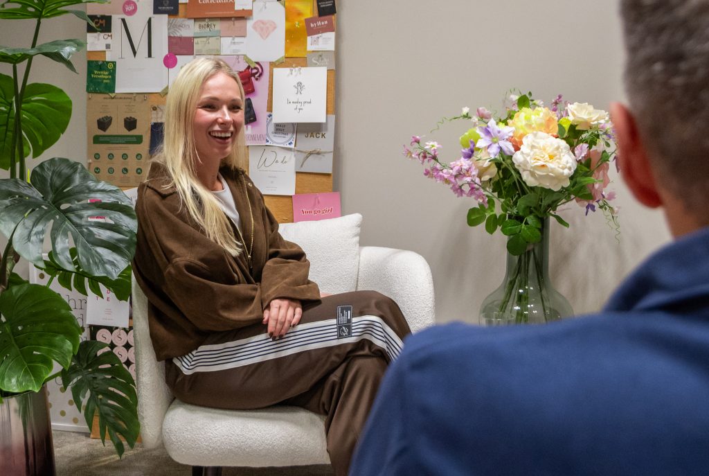 Vrouw glimlacht tijdens interview in kantoor met bloemen