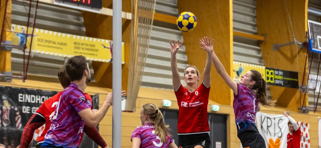 Korfbalspelers in actie met bal in de lucht.