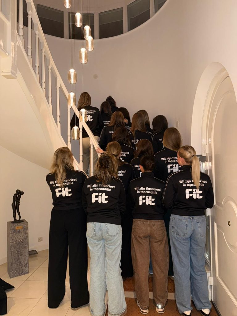 Groepje mensen met jassen op trap in ronde ruimte.